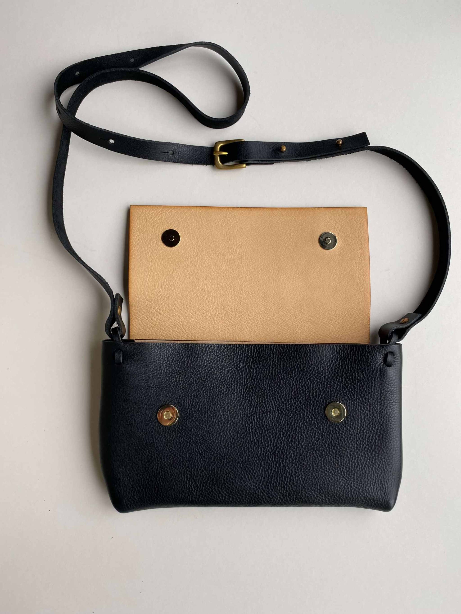 Minimalist Fold Leather Crossbody Bag in black with pebbled texture and adjustable strap.