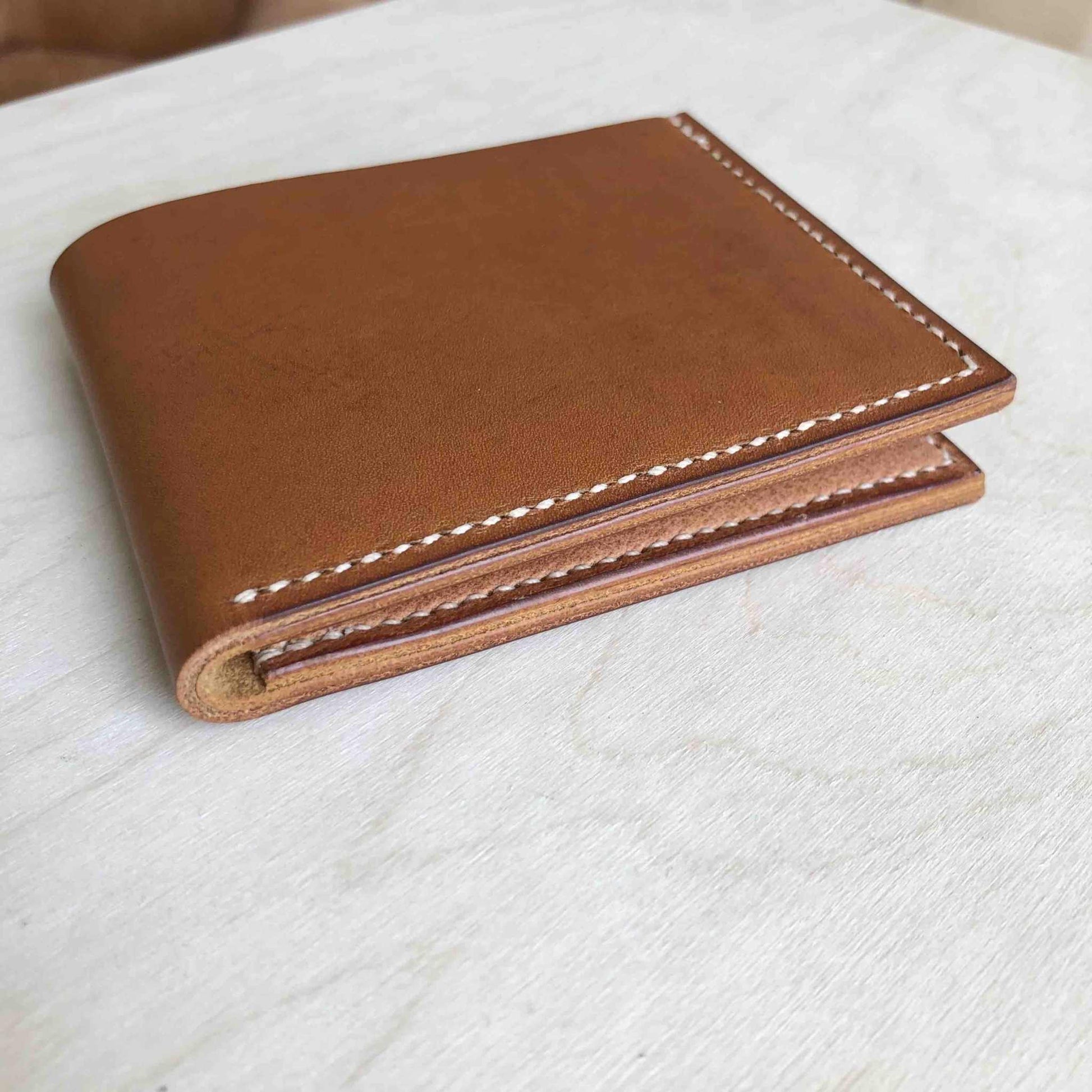 Handmade tan leather wallet with white stitching, crafted in the UK.