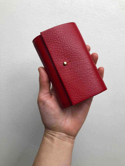 Red leather women's wallet with brass stud closure, handcrafted in sustainable leather, compact design.