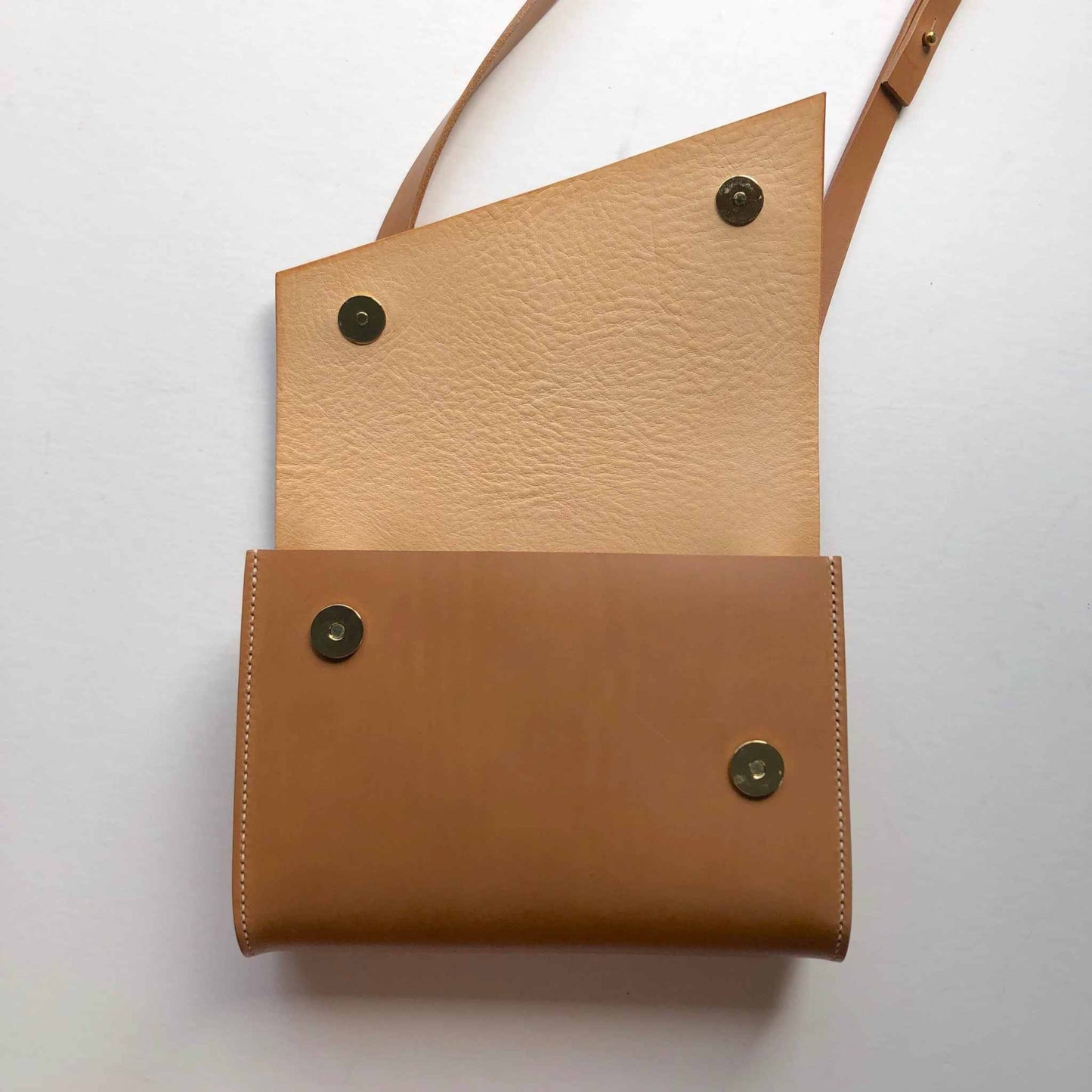 Tan leather crossbody bag with adjustable strap and card holder, handcrafted for minimalist style.