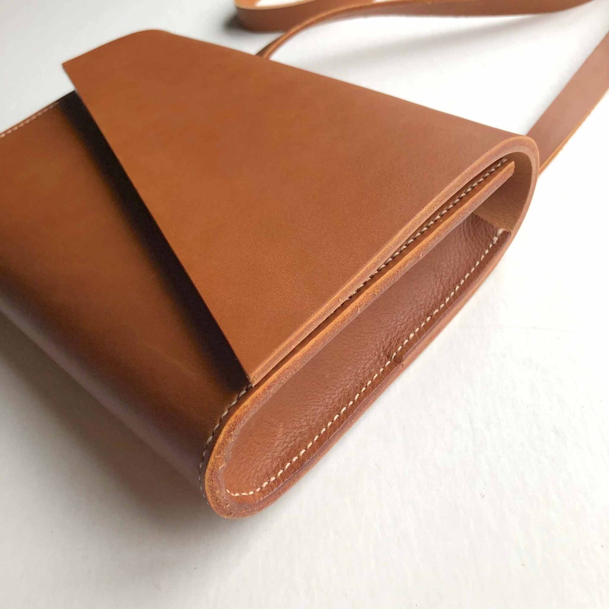 Tan leather crossbody bag with adjustable strap and minimalist design.