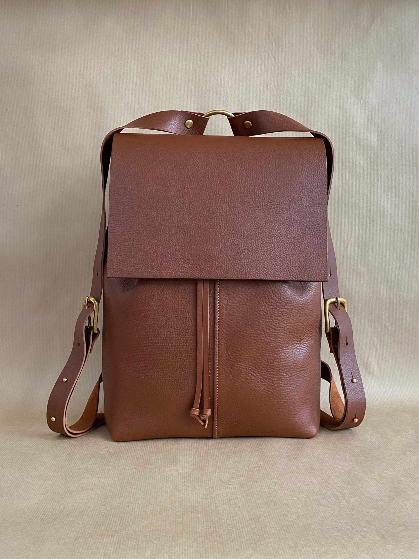 Tan leather backpack with a squared flap design, adjustable straps, crafted from premium leather by CARV.