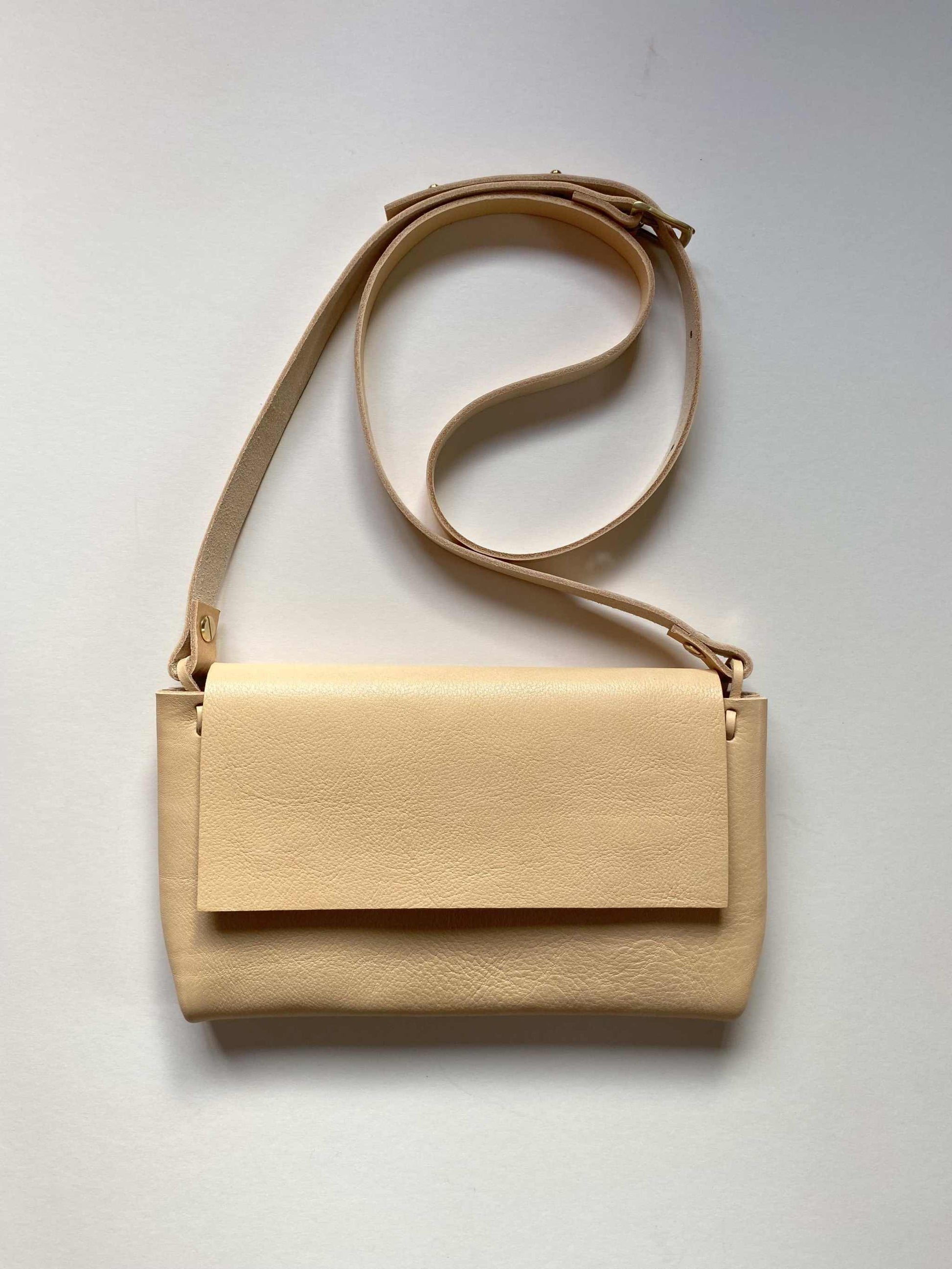 Minimalist Fold Leather Crossbody Bag in natural color with adjustable strap and structured design, handcrafted from sustainable pebbled leather.