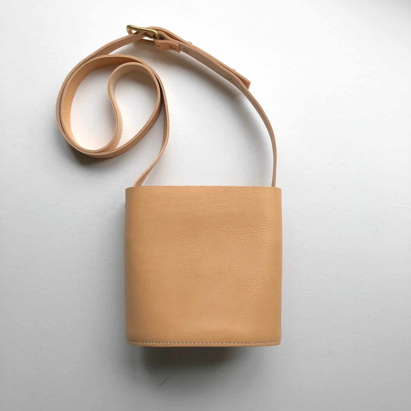 Oval Mini Leather Bag made of natural grain leather with adjustable strap.