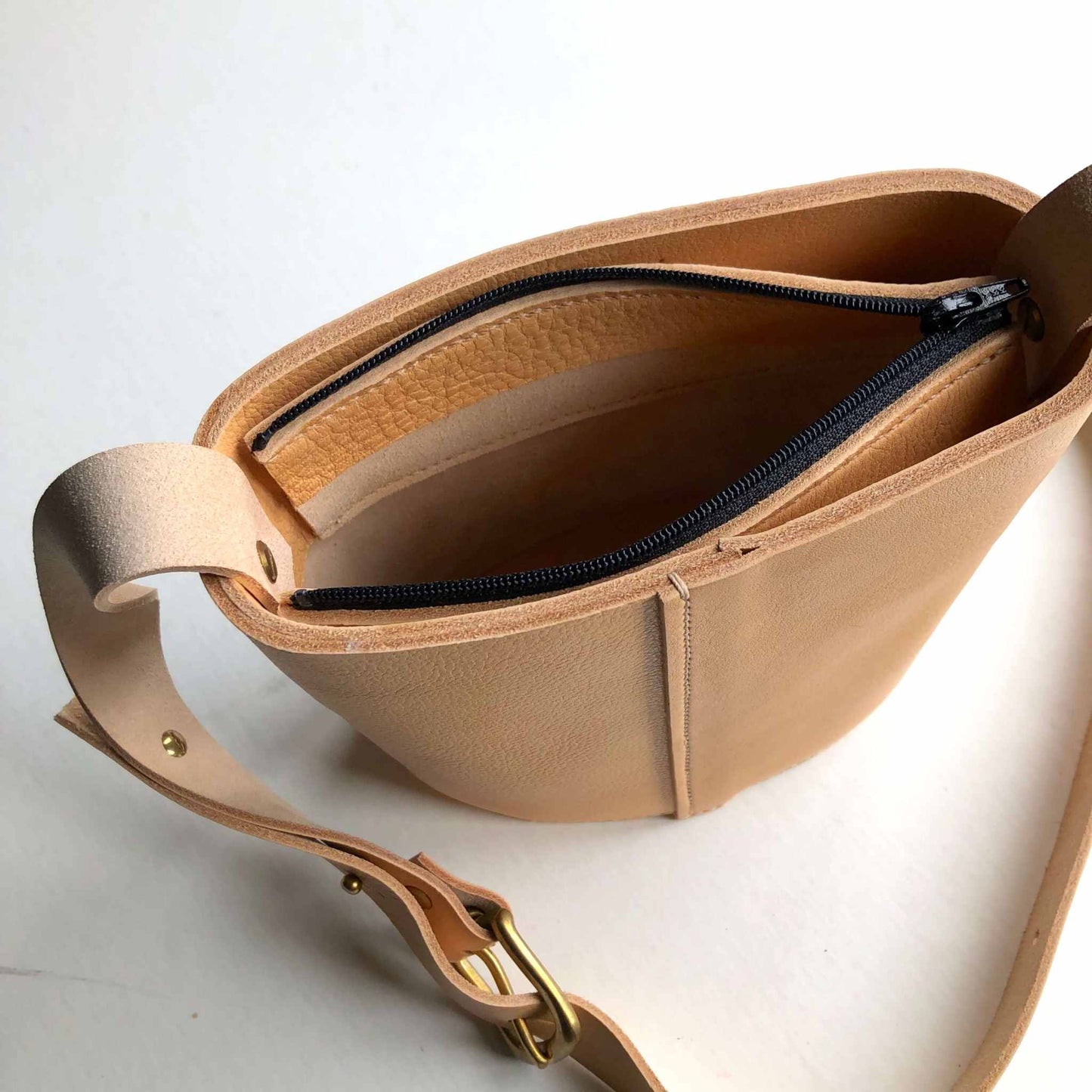 Oval Mini Leather Bag with natural grain finish and adjustable strap.