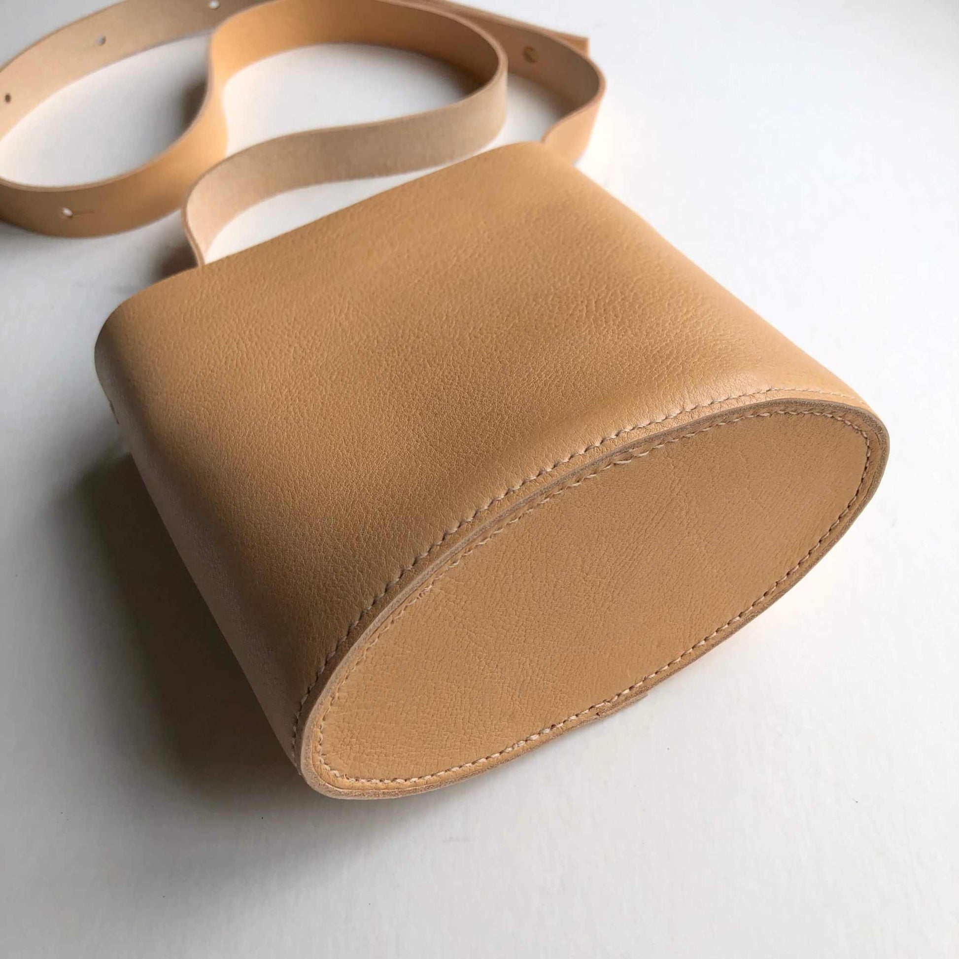 Oval Mini Leather Bag made from natural raised grain leather with adjustable strap.