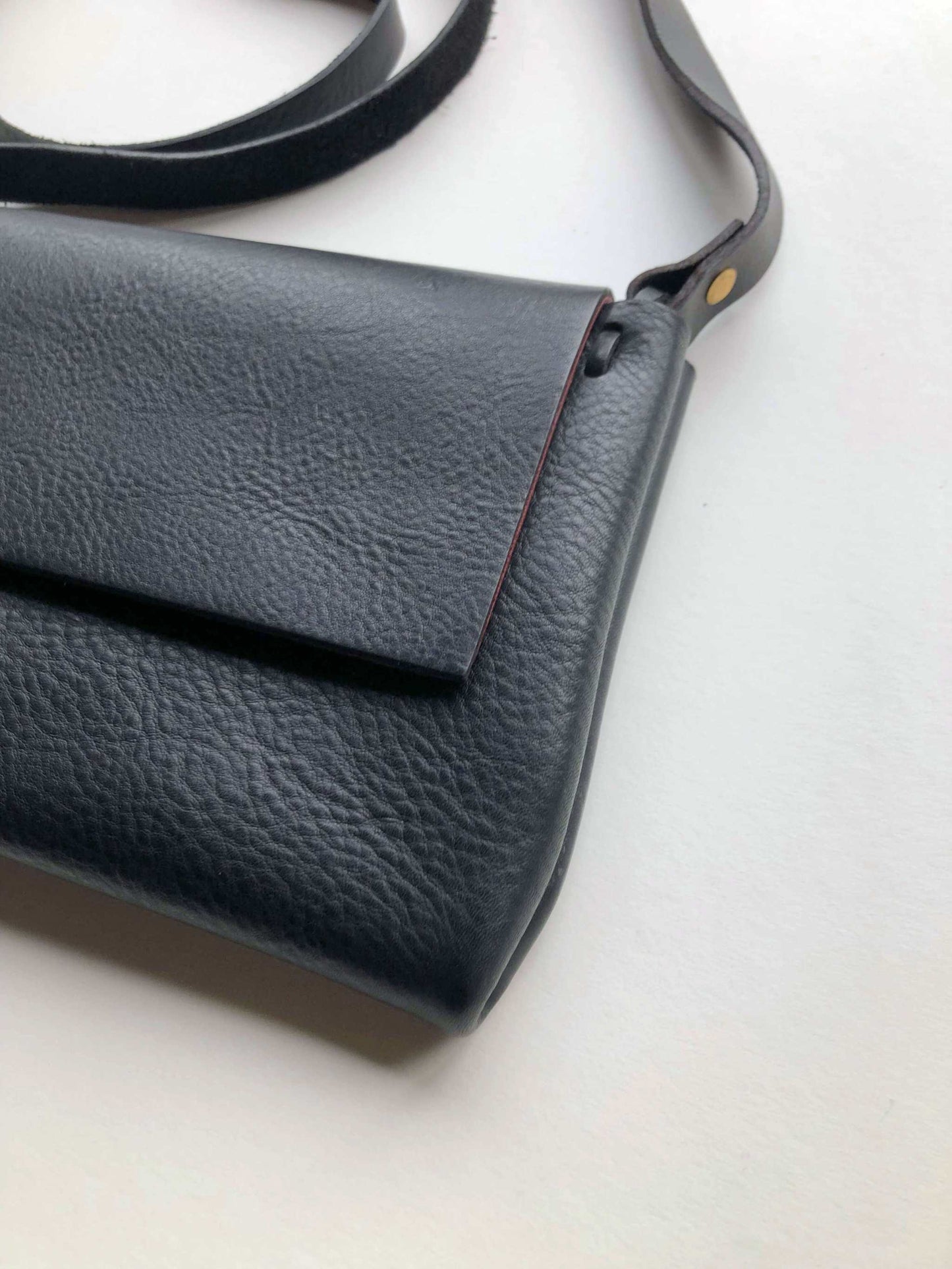 Minimalist Fold Leather Crossbody Bag in black with adjustable strap and pebbled texture.