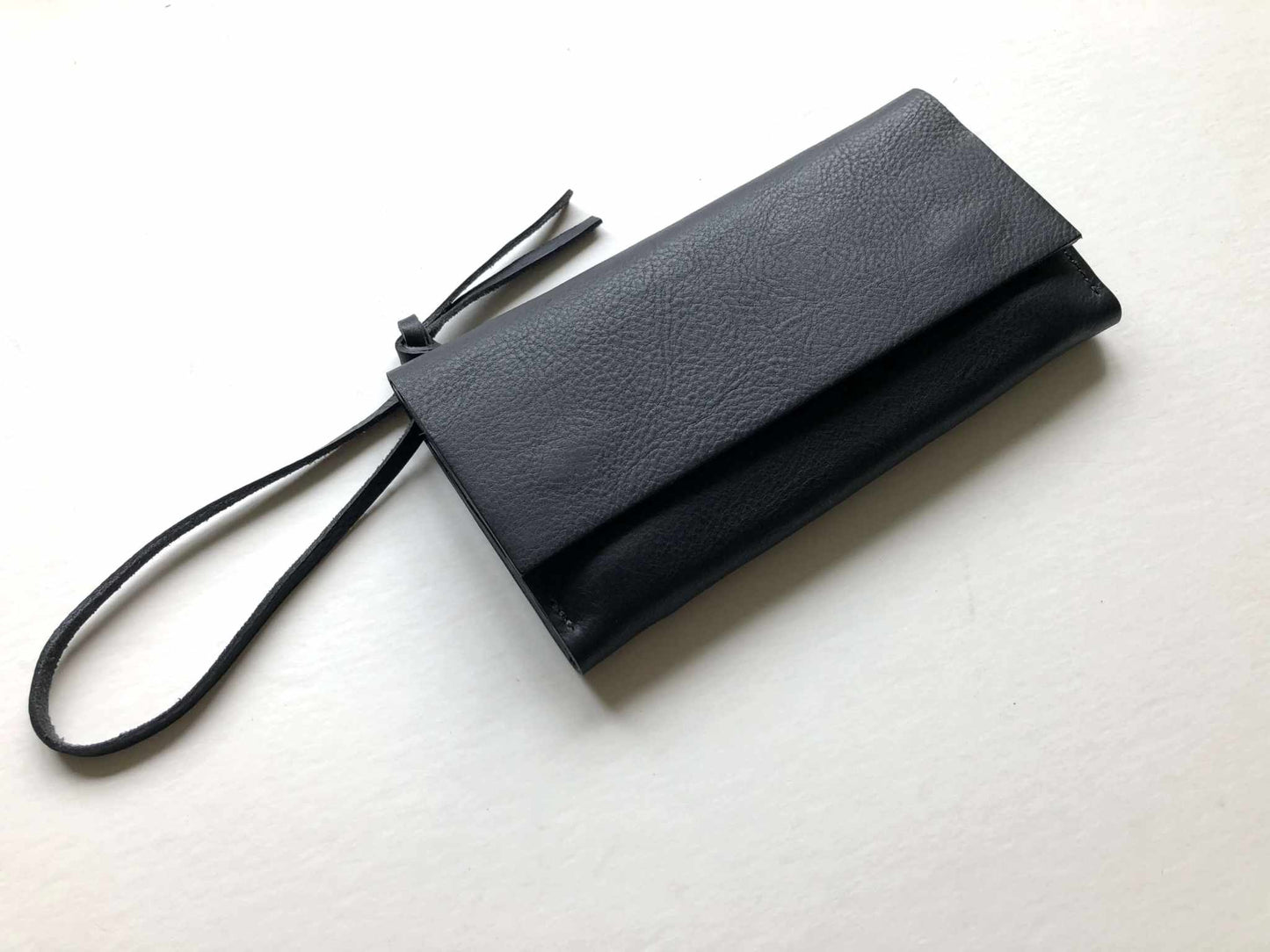 Knot Leather Purse Wallet in black with optional wrist strap, featuring vegetable-tanned leather and minimalist design.