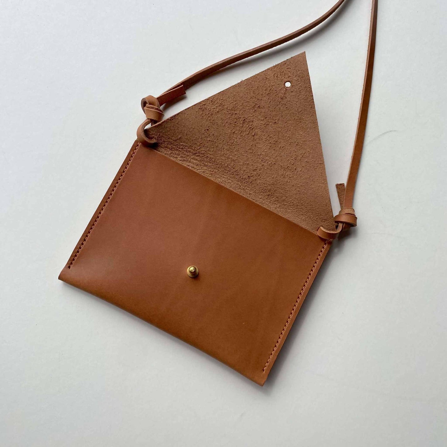 Drifter Mini Pocket Bag in cognac tan leather with triangular flap and brass press stud closure.