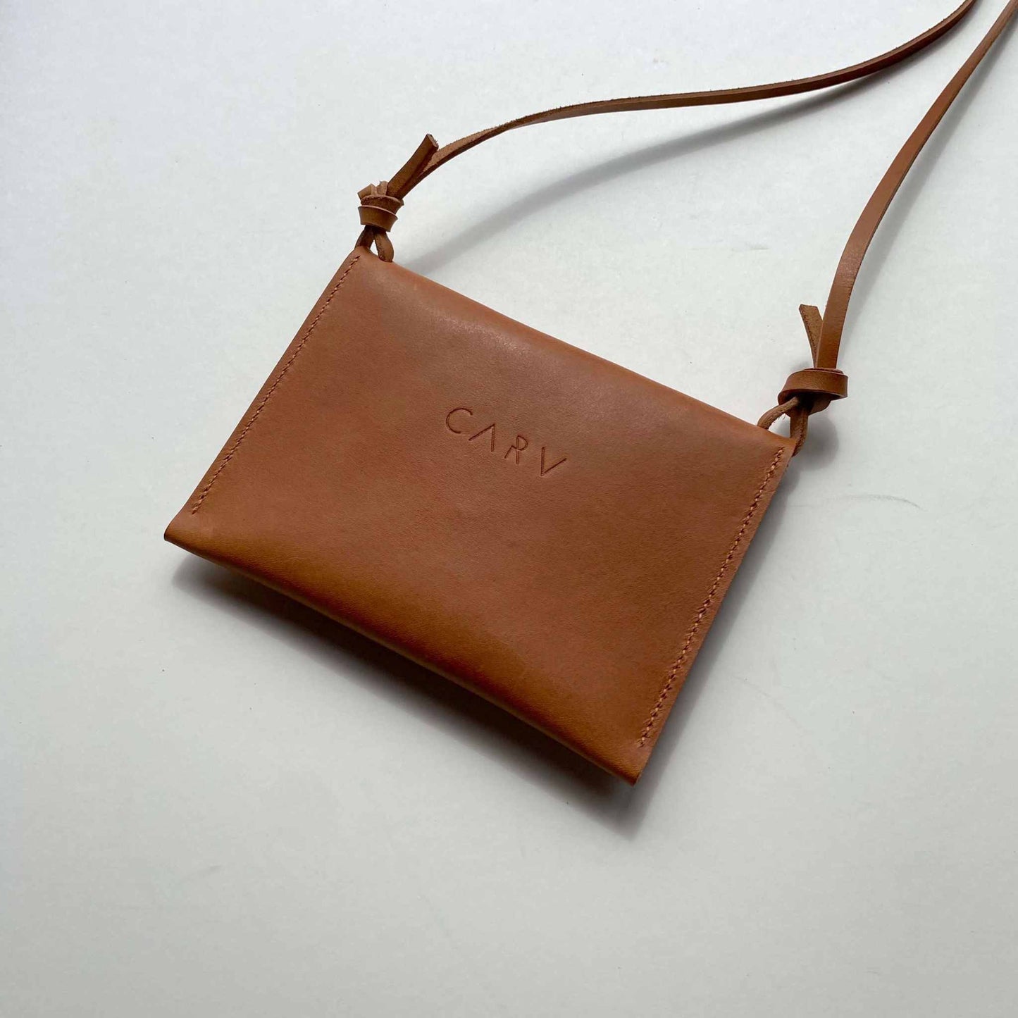 Drifter Mini Pocket Bag in cognac tan leather with minimalist design and brass closure.