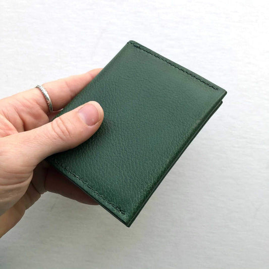 Green leather card wallet in hand, showcasing artisanal craftsmanship and minimalist design.