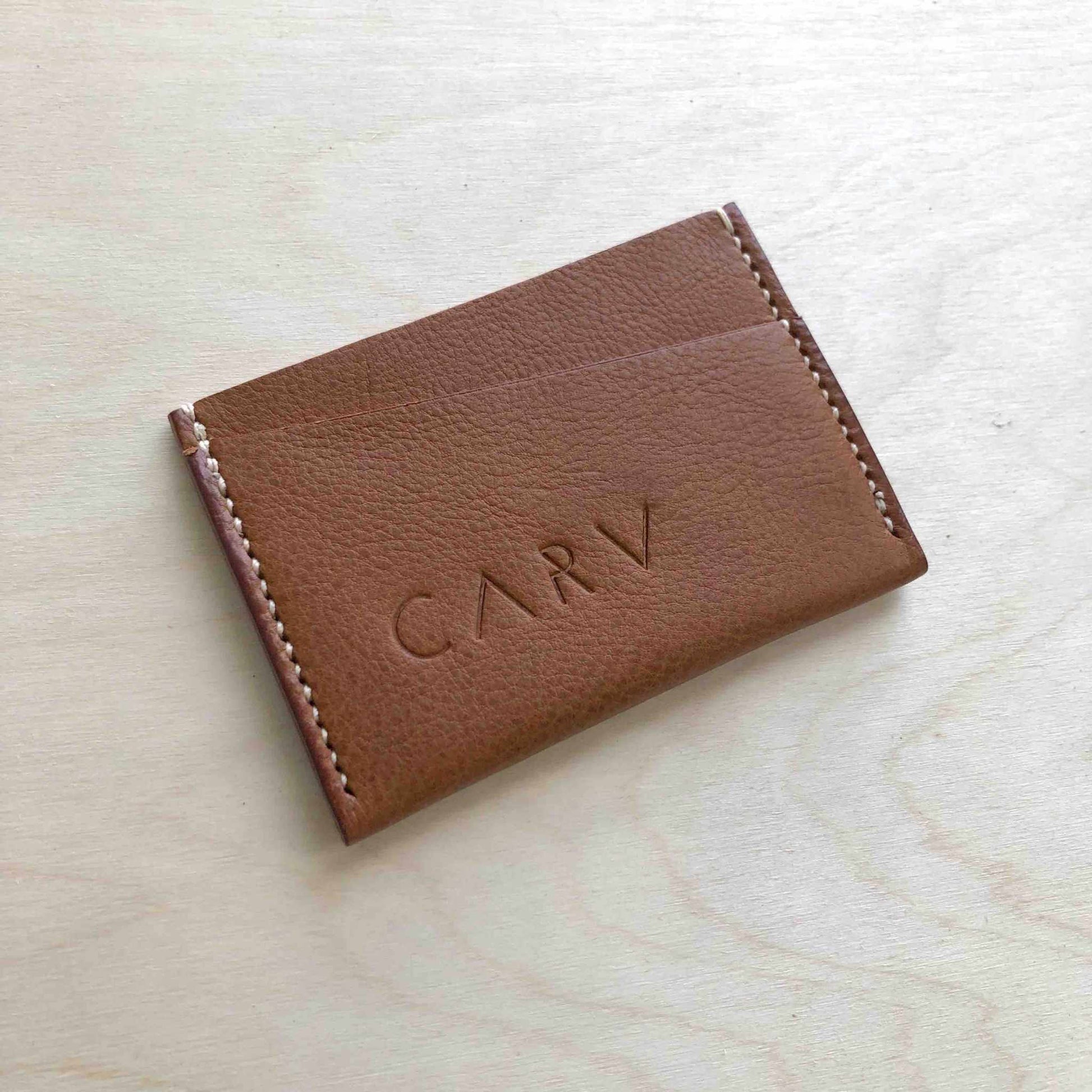 Green leather card holder with embossed logo, minimalist bifold design.