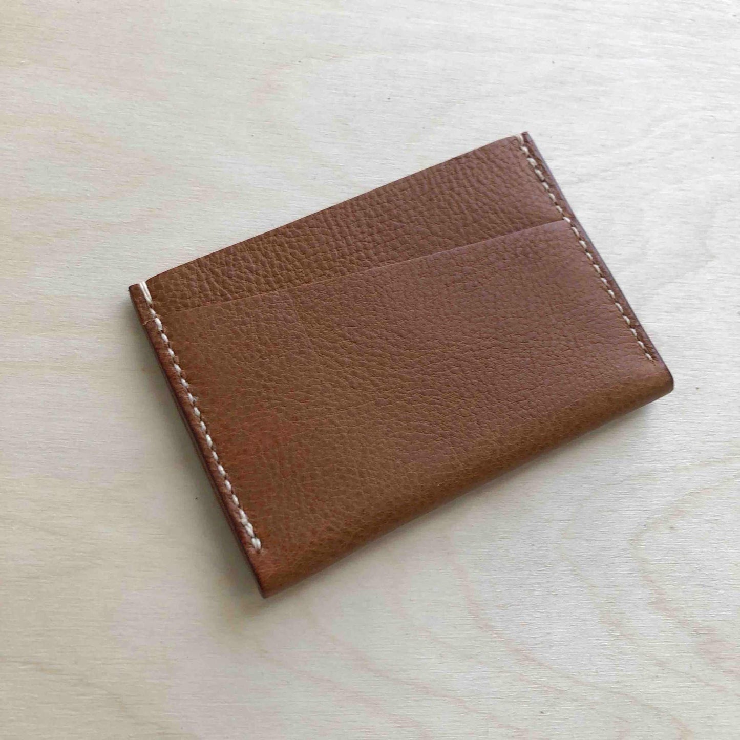 Green leather card holder with a minimalist bifold design, crafted from vegetable-tanned leather.