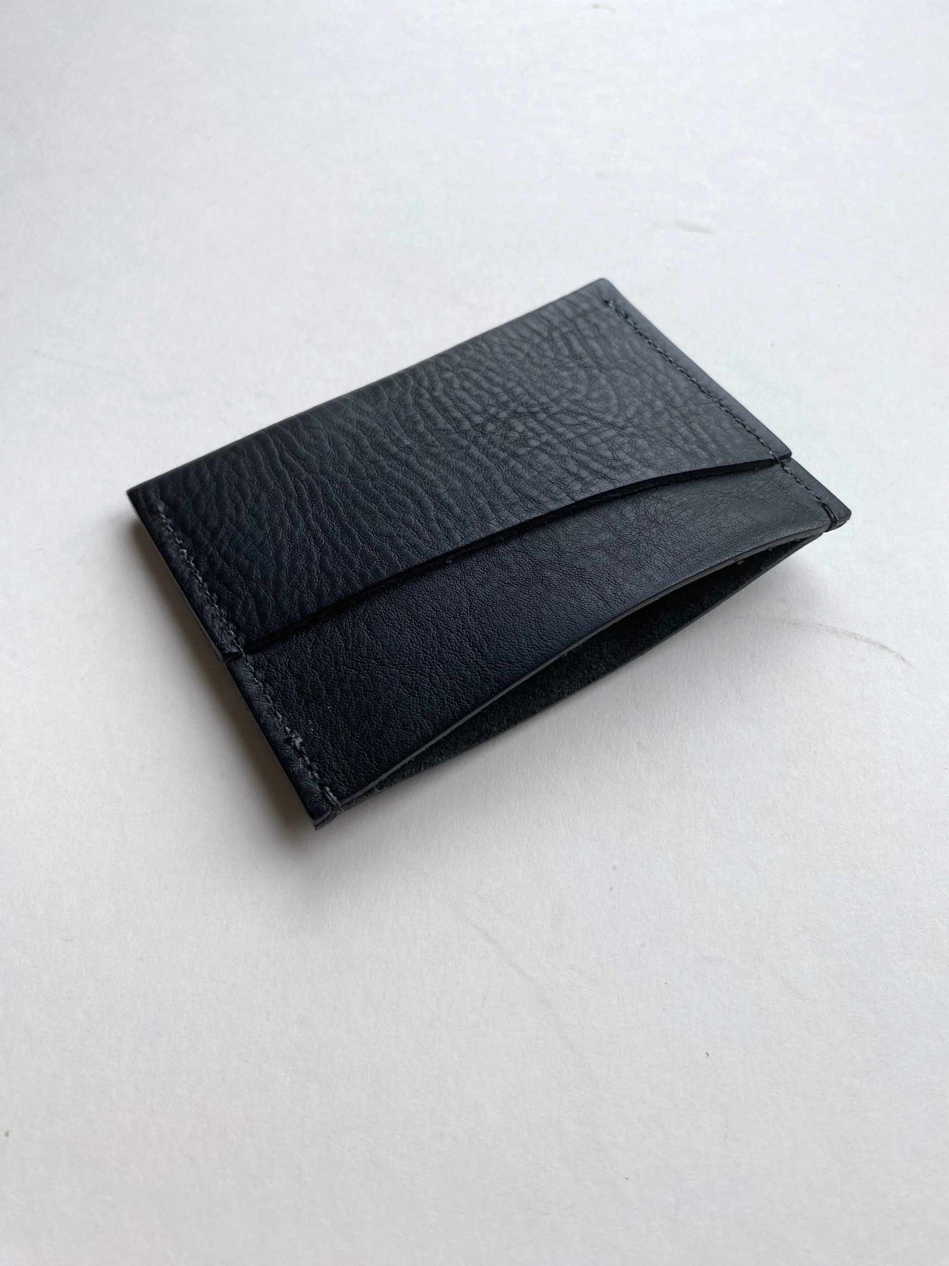 Green leather card holder with minimalist bifold design.