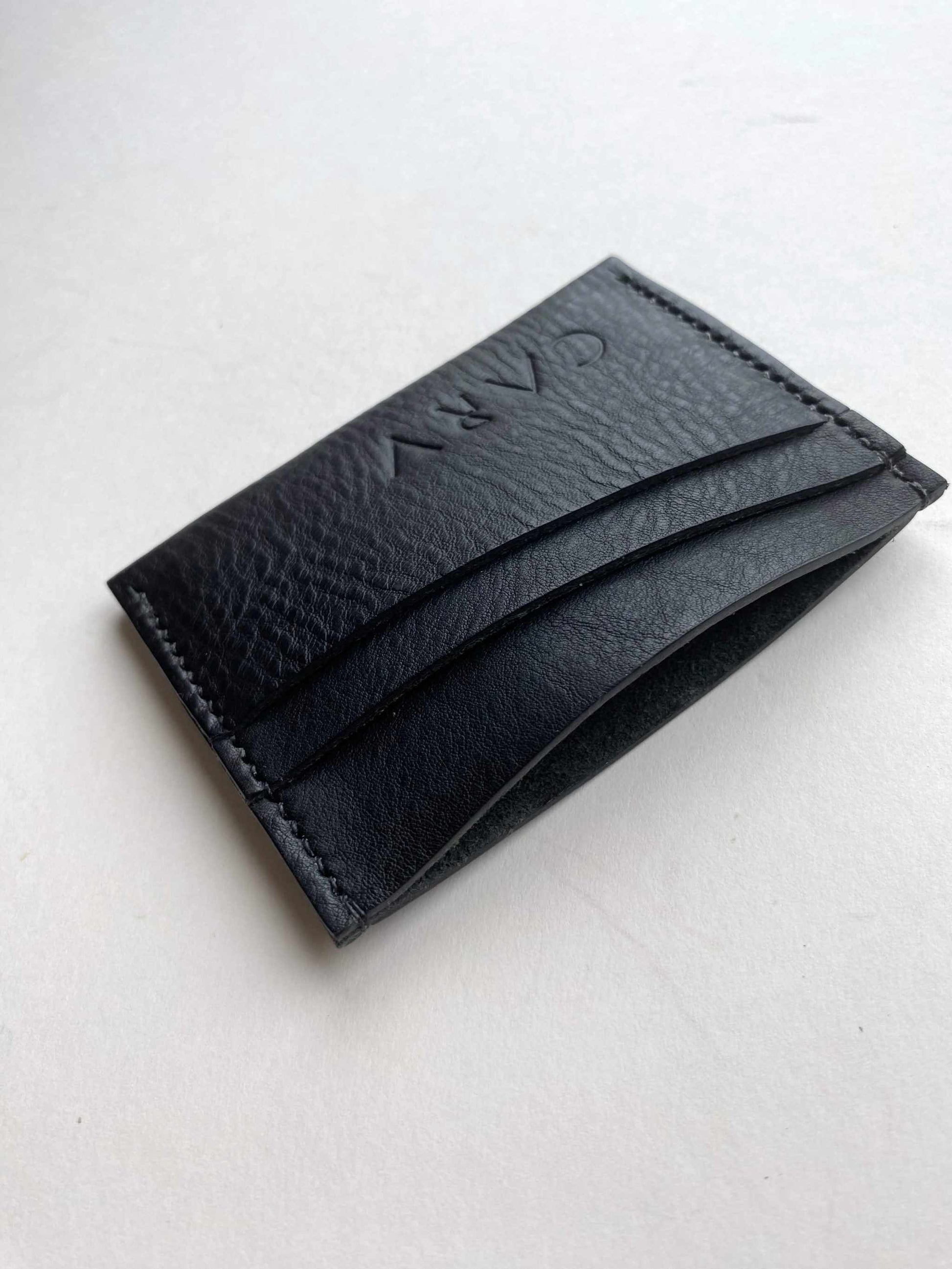 Green leather card holder with bifold design and card slots.