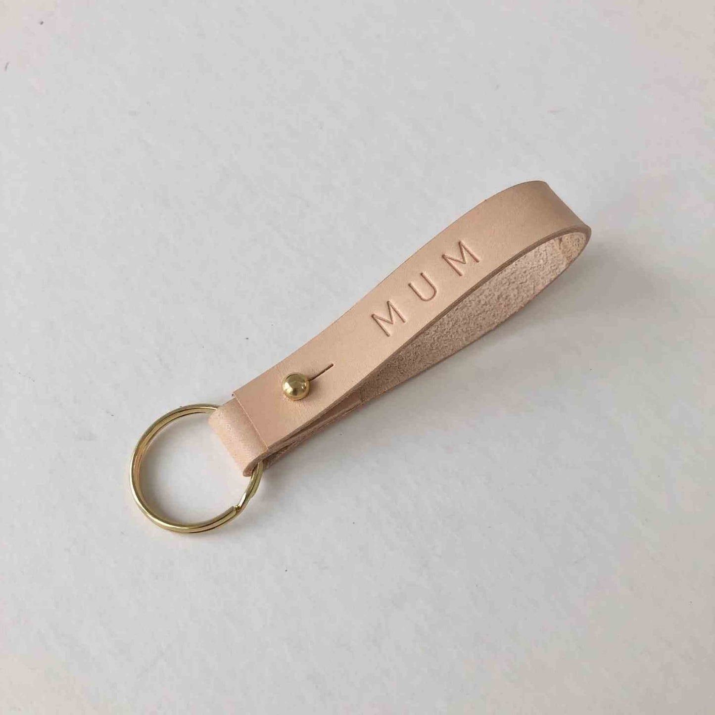 Personalised leather keyring with embossed initials in natural color, crafted in the UK.