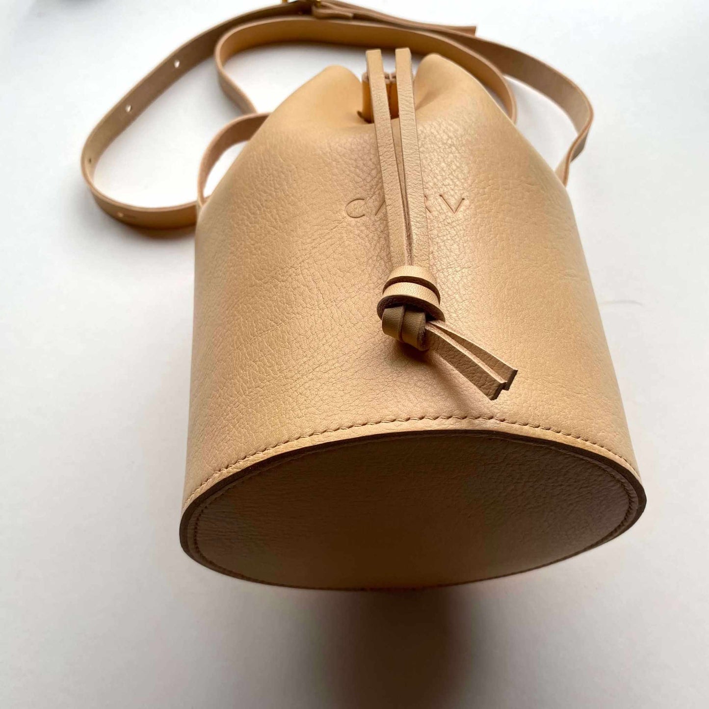 Cylinder Leather Bucket Bag in natural color, handcrafted in the UK, made from vegetable-tanned leather with adjustable strap and brass buckle.