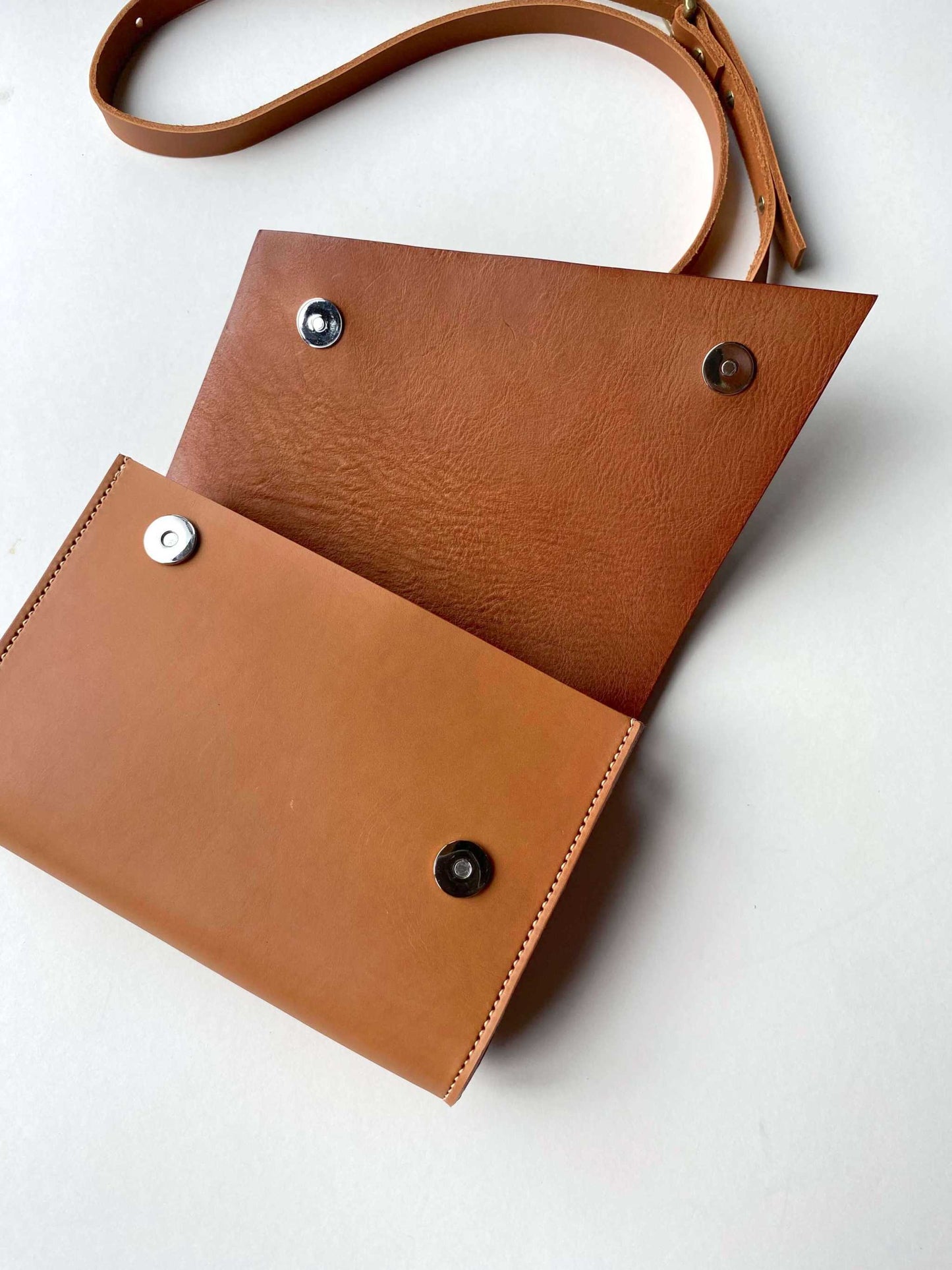 Tan leather crossbody bag with adjustable strap and secure magnetic closure.