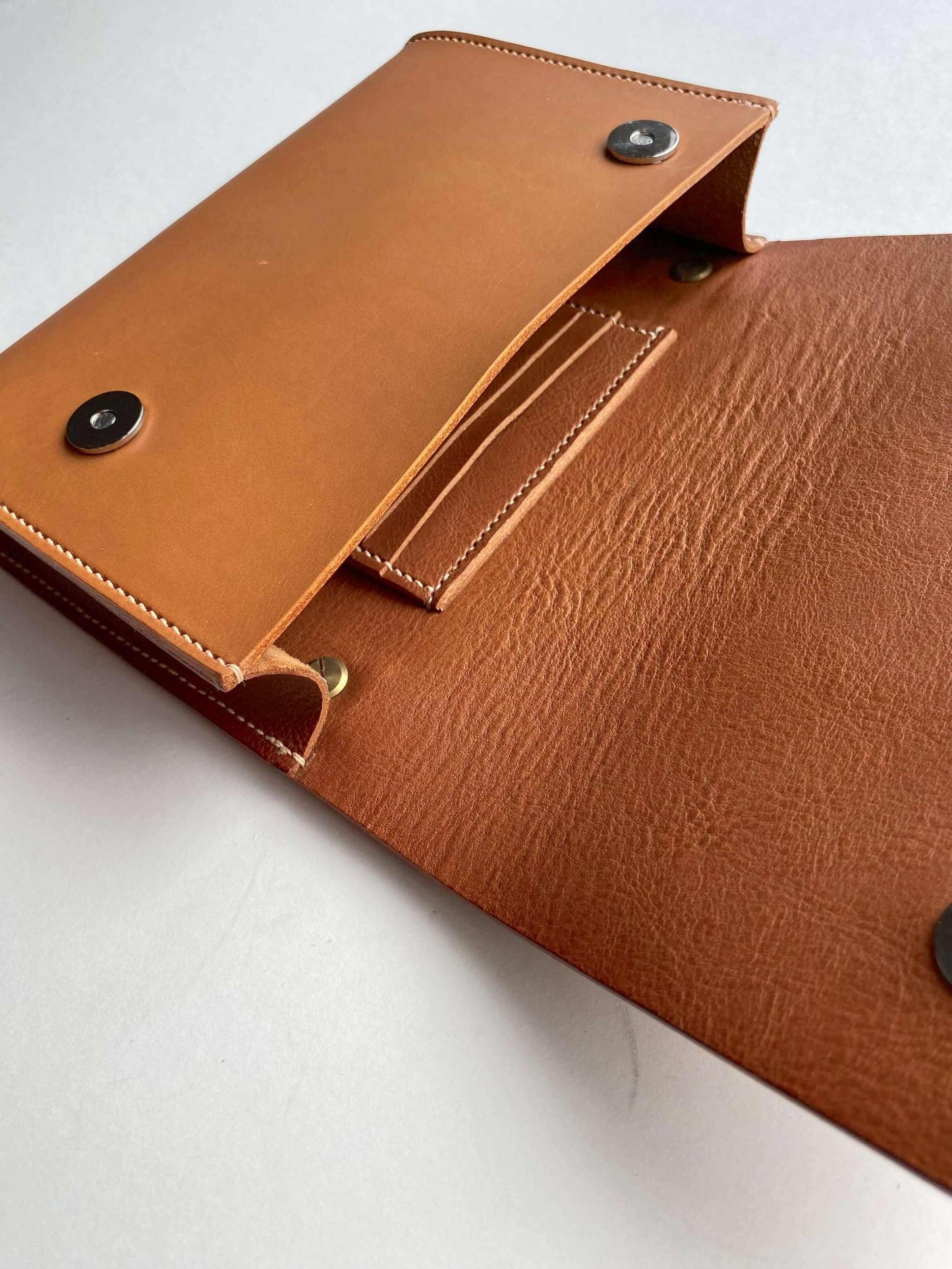 Tan leather crossbody bag with card holder and button closure.