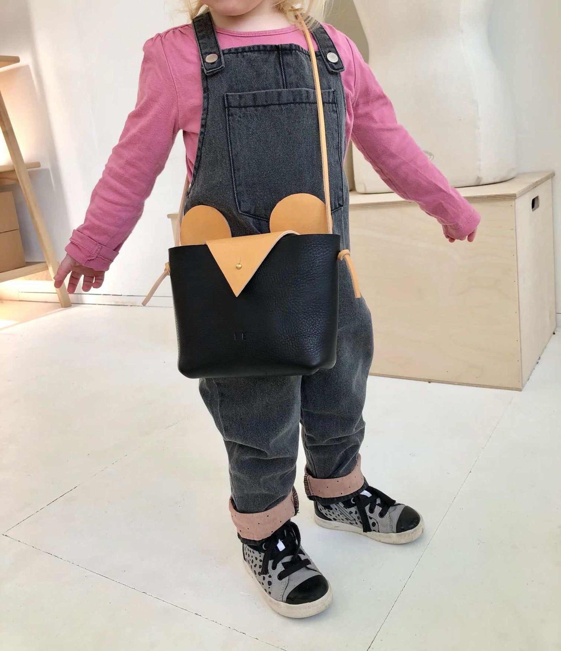 Little Robot Crossbody Bag held by child, showcasing black leather with natural ears and nose, perfect for kids and adults.