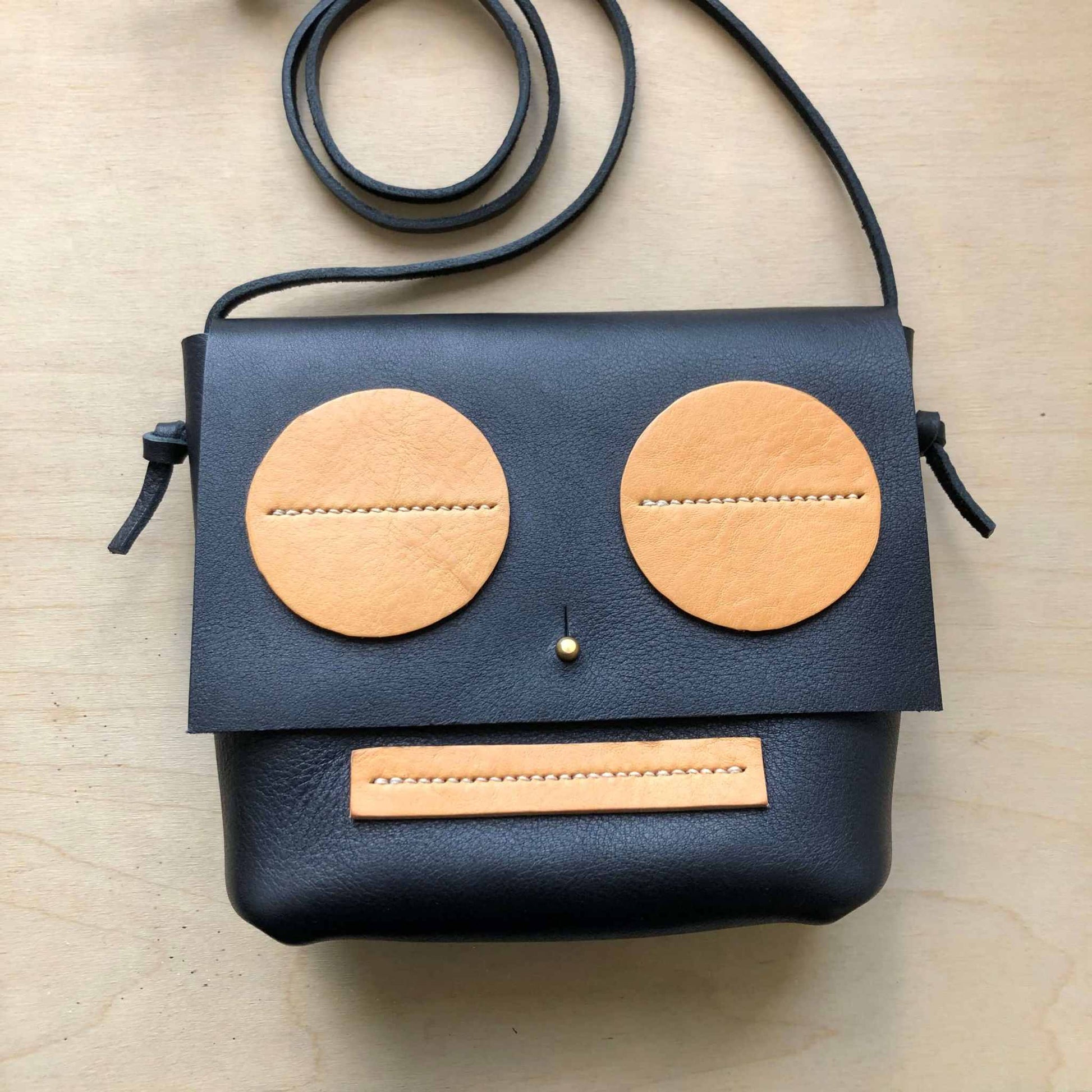 Little Robot Crossbody Bag, black leather with natural accents, handcrafted in the UK, playful design, brass hardware.