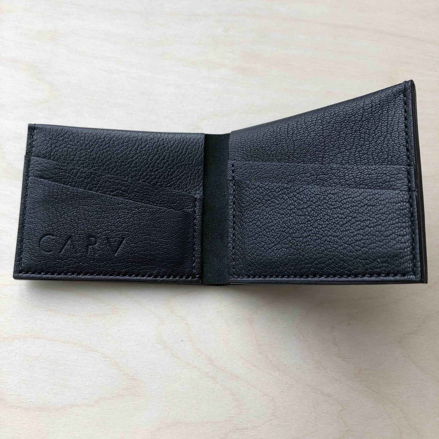 Handmade black leather bifold wallet crafted in England with card slots and sustainable vegetable-tanned leather.