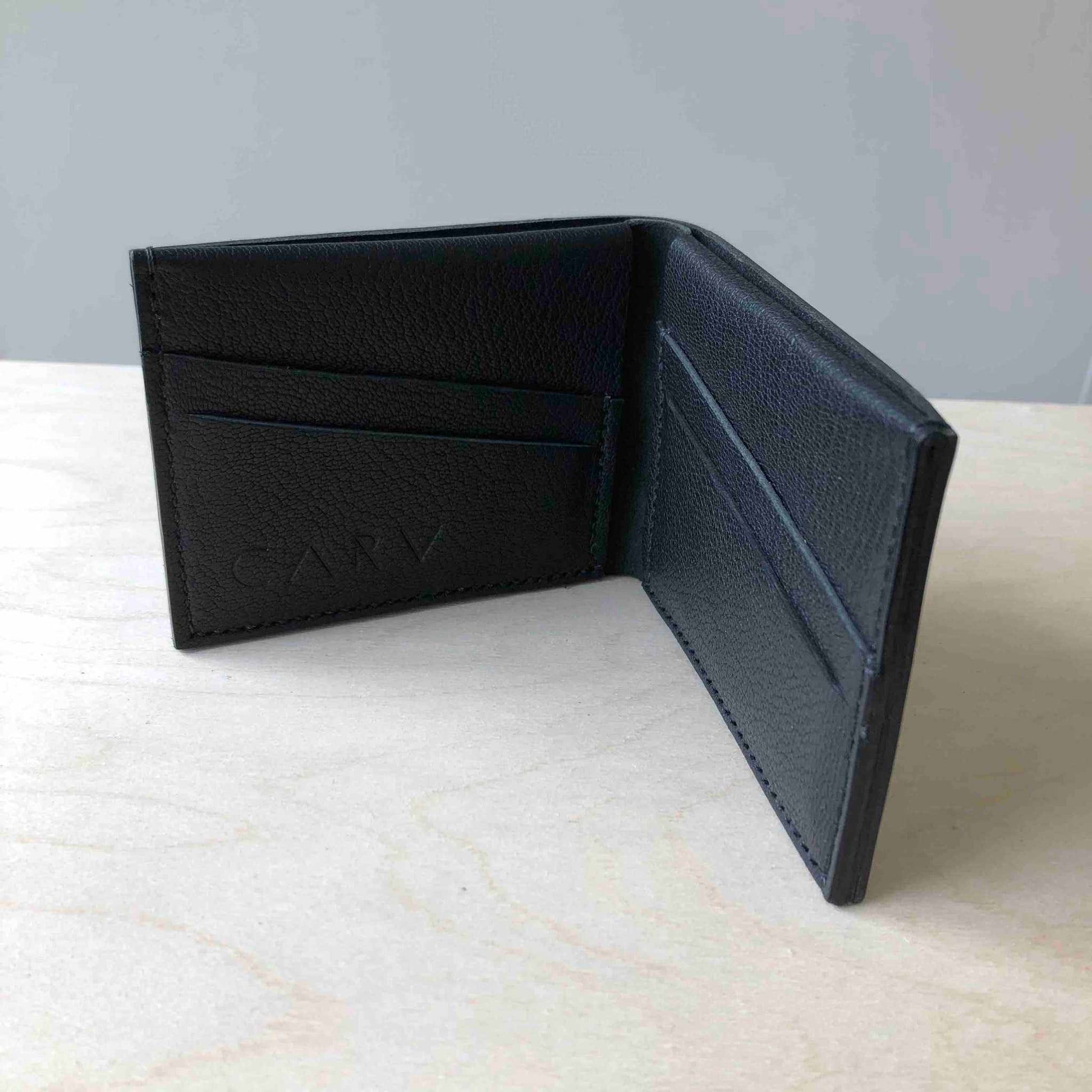 Handmade Black Leather Bifold Wallet with card slots on wooden surface.