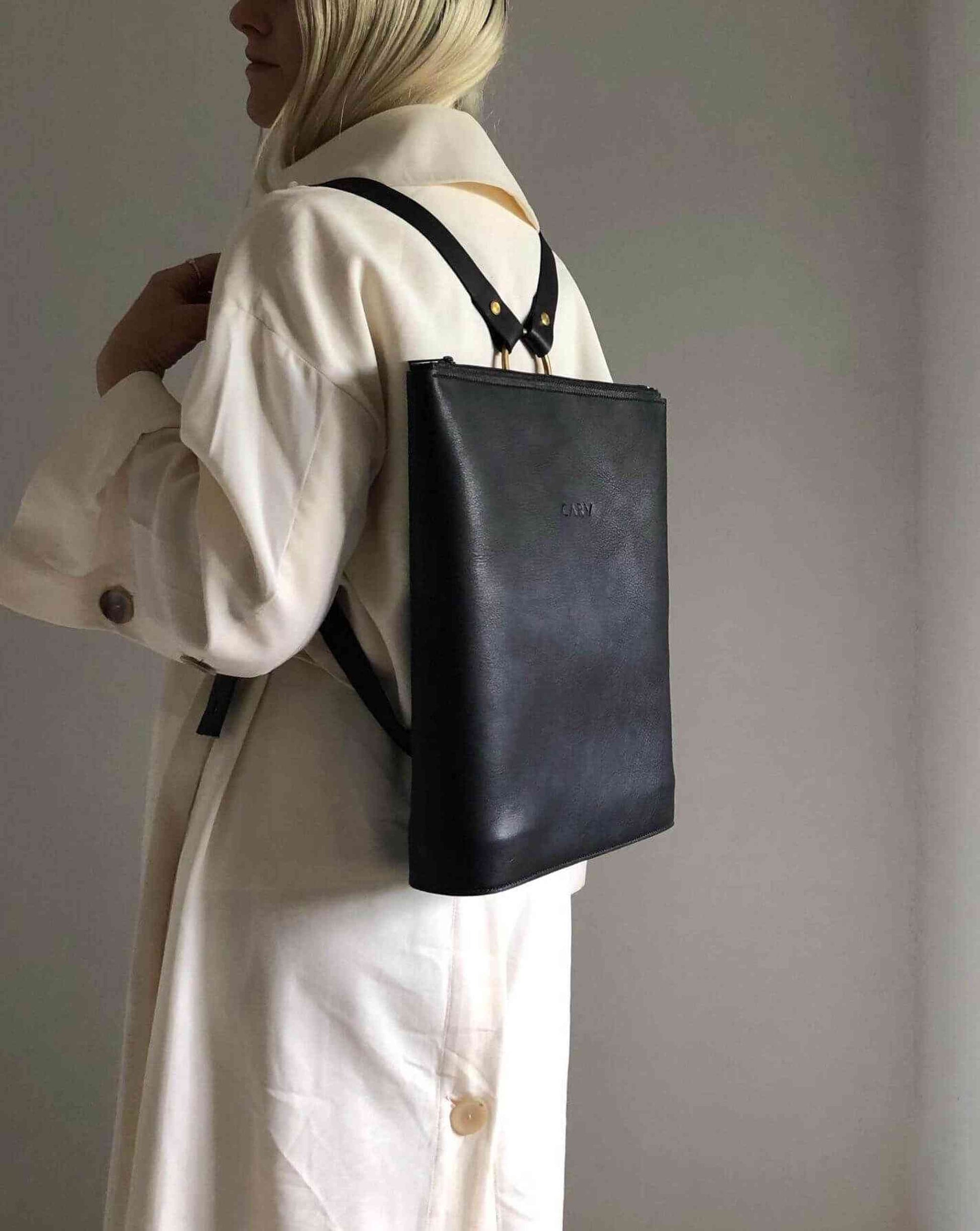 Minimalist Vita Black Leather Backpack by CARV styled on someone wearing a white coat.