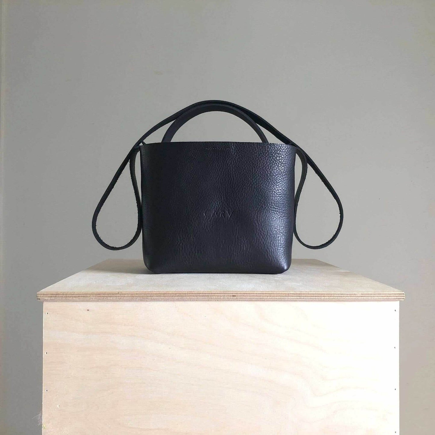 Black Basket Mini Leather Tote Bag by CARV, handcrafted UK, sustainable vegetable-tanned leather, versatile design with adjustable straps, detachable pocket, available in Black, Tan, or Natural.