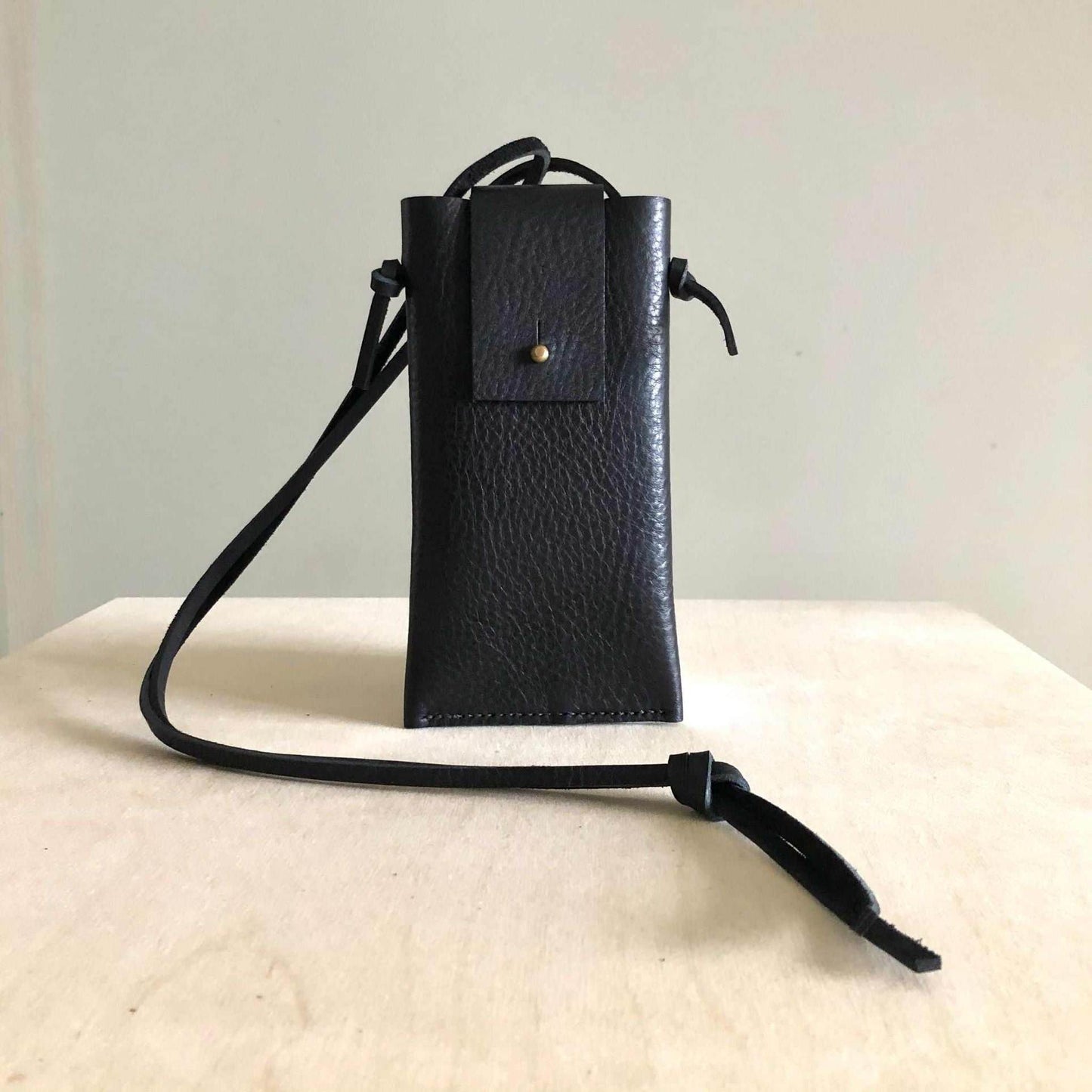 Knot Leather Crossbody Phone Bag in Black with adjustable strap, sustainably sourced, handmade in UK.