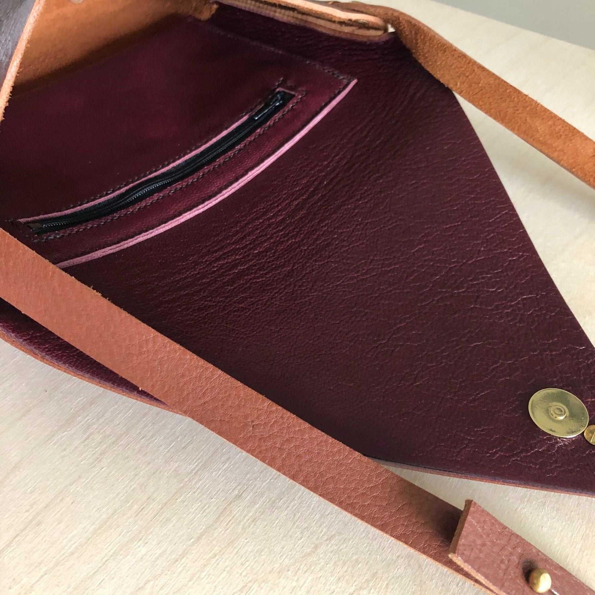 Drifter Leather Crossbody Bag in Tan, showing burgundy lining with zip pocket and brass closure.