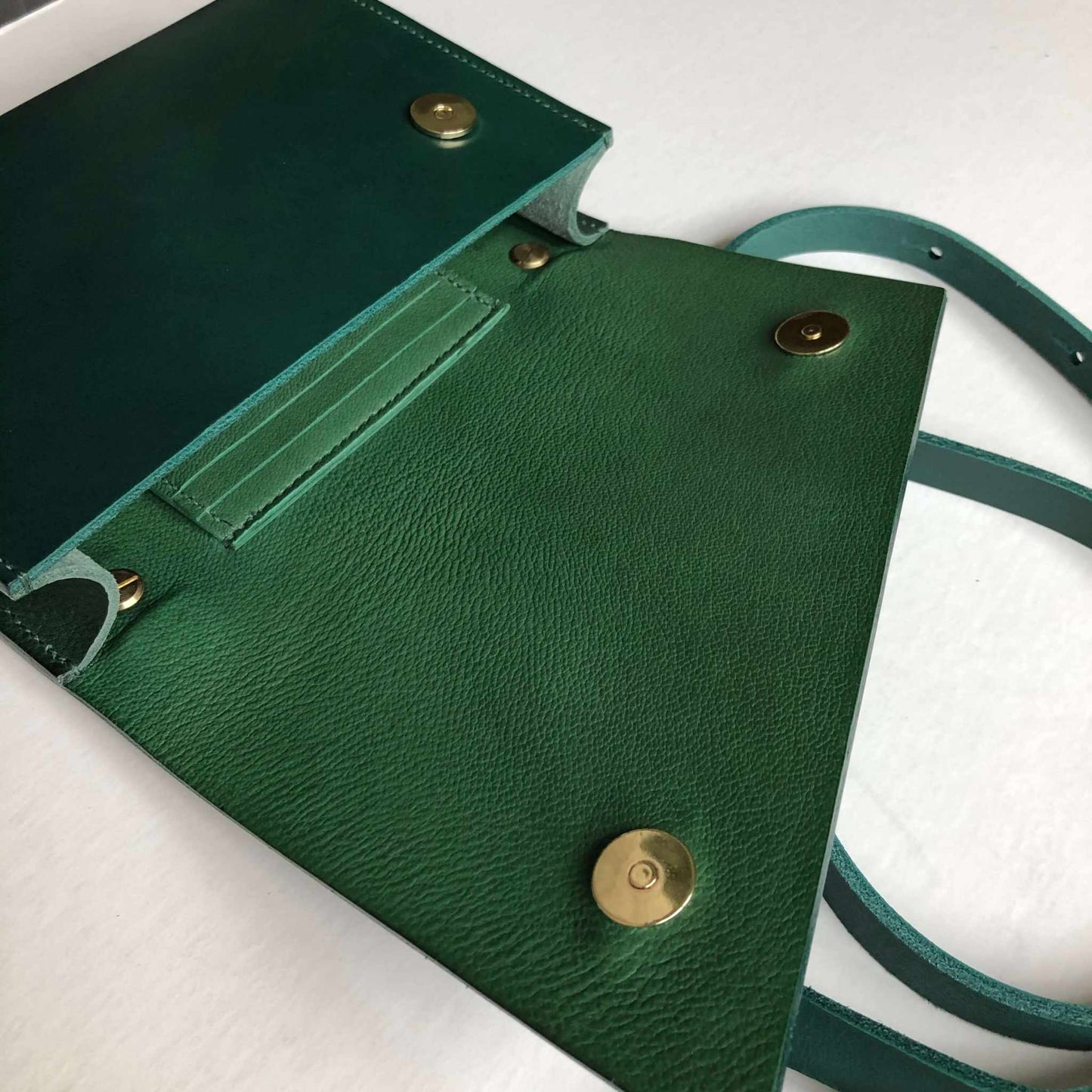 Green leather crossbody bag with adjustable strap and cardholder, showcasing vegetable-tanned craftsmanship.