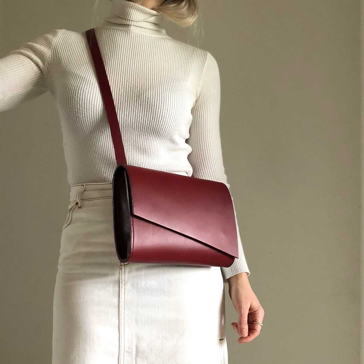 Red leather crossbody bag with asymmetrical flap design and adjustable strap.