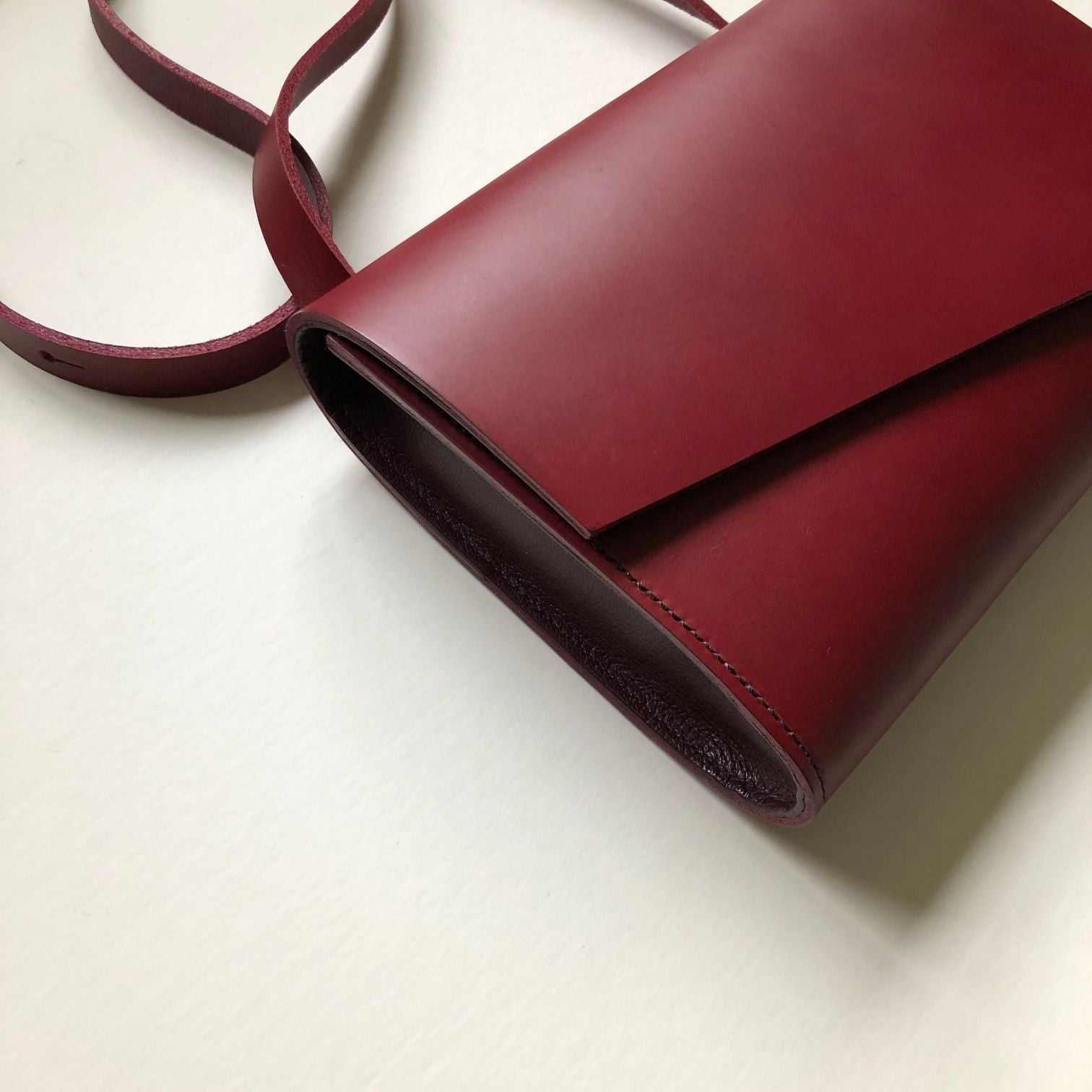 Red leather crossbody bag with asymmetrical flap, handcrafted from sustainable vegetable-tanned leather.