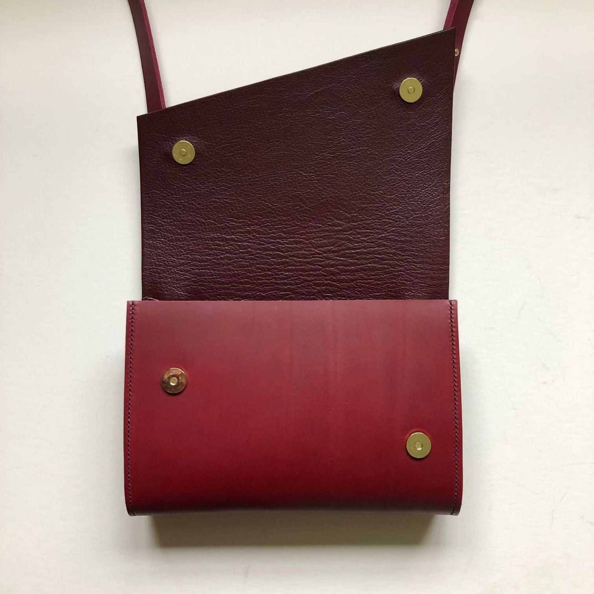 Red Leather Crossbody Bag with Asymmetrical Flap and Adjustable Strap.